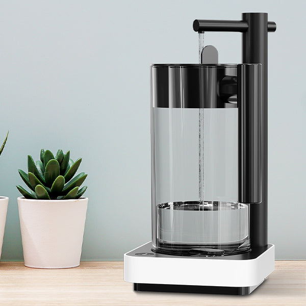 A modern black and white electric water dispenser filling a clear glass on a wooden surface, with two small potted succulent plants placed beside it, against a light blue wall background.